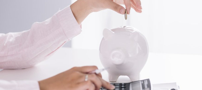 Žena stavlja novac u štednu kasicu