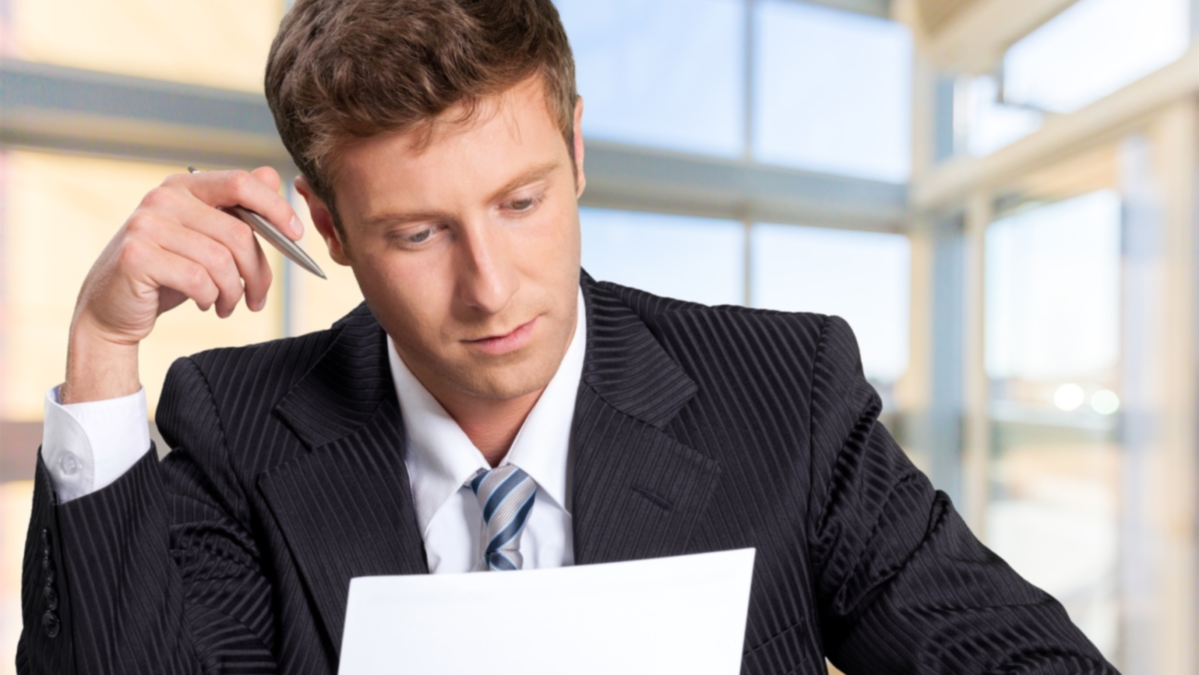 Mladi muškarac u odijelu čita dokument