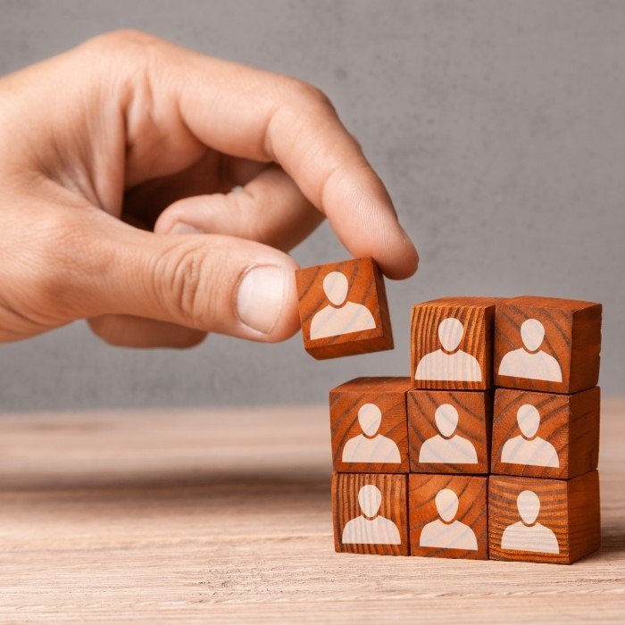 Ljudska ruka slaže drvene kocke sa siluetama gornjeg dijela trupa