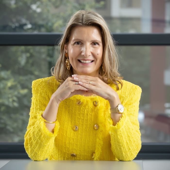 Tanja u žutom sakou, drži ruke ispod brade, a na licu ima osmijeh