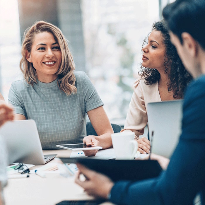 Tri nasmijane osobe za stolom u uredu