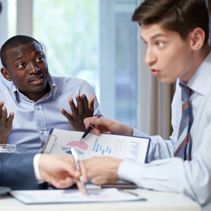 Dva mlađa muškarca raspravljaju sjedeći za stolom