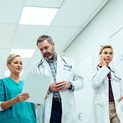 Dvoje liječnika i medicinska sestra hodaju bolničkim hodnikom.