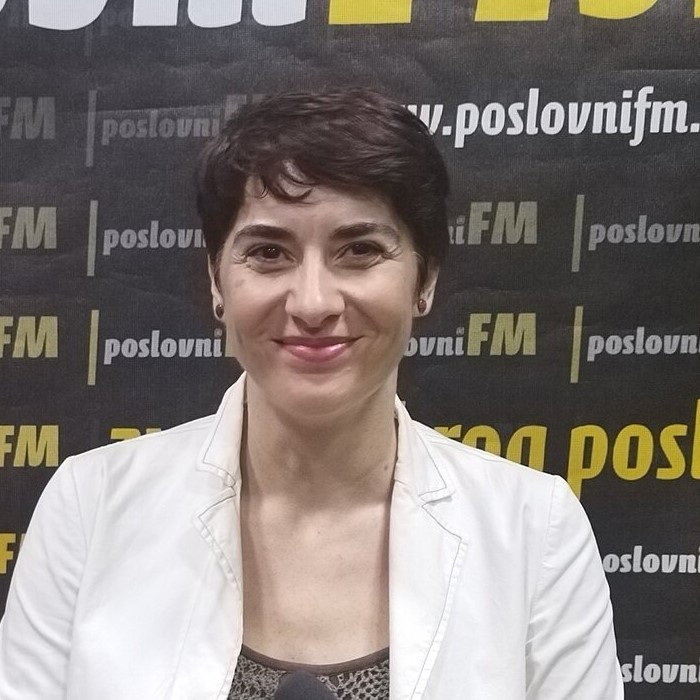 Žena u bijelom sakou u studiju za mikrofonom