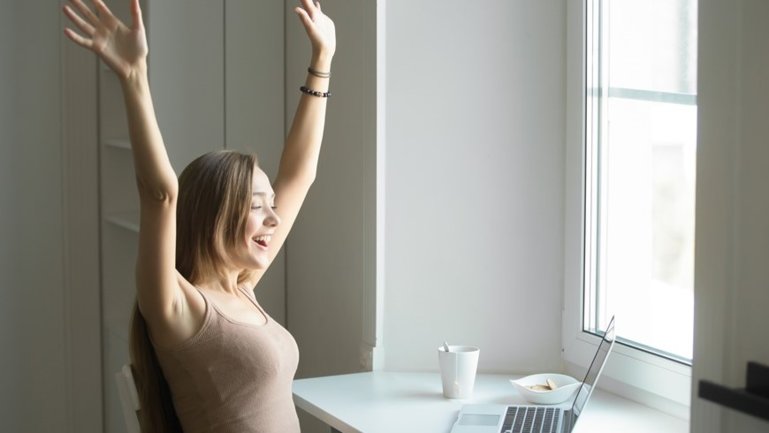 Fotografija prikazuje djevojku za laptopom koja je u dobrom raspoloženju