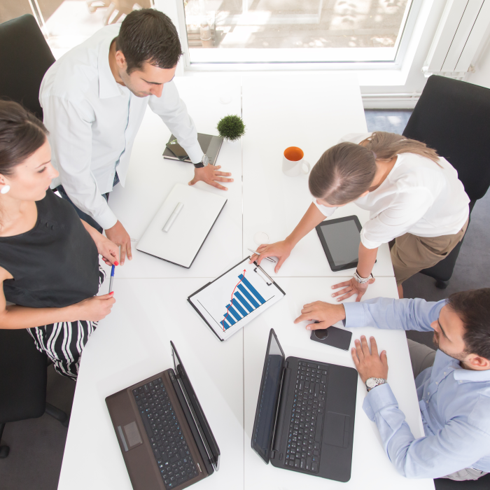 grupa ljudi planira za uredskim stolom punim papira i računala