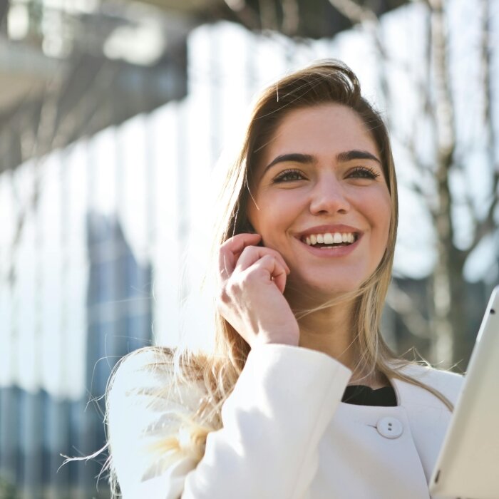 žena u bijeloj majci telefonira i drži tablet