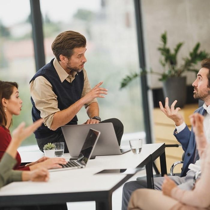 pet sređenih kolega sjede za stolom i raspravljaju o nekoj temi